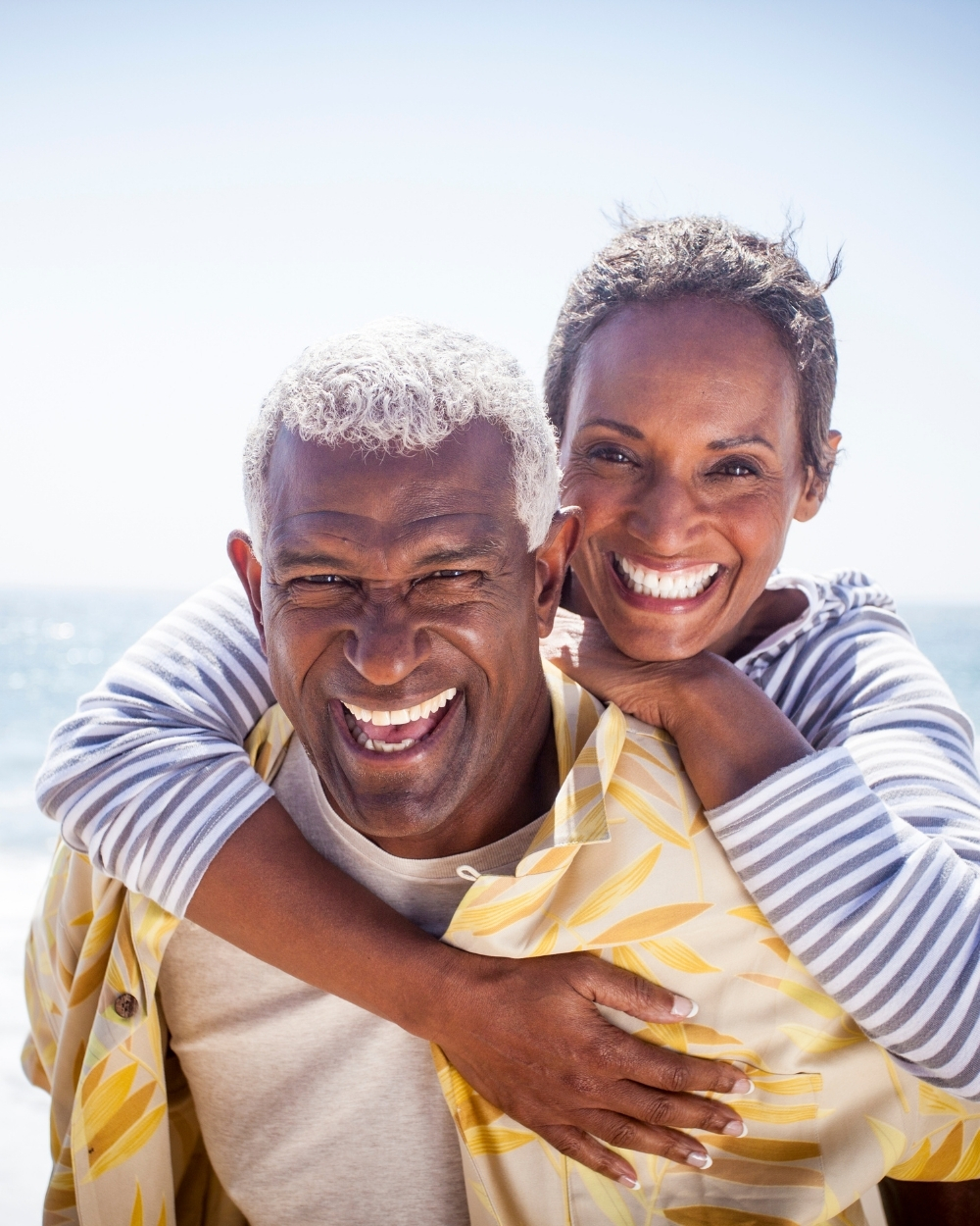 Side view of a tan two-story building with balconies, surrounded by green grass and trees on a sunny day.